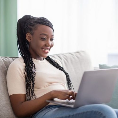 Happy black woman freelancer working from home, using modern laptop